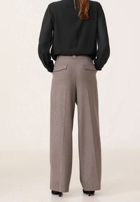 Höga, vida byxor i ett brunt och vitt rutmönster med bakfickor, texturerad tyg och skräddarsydd passform.