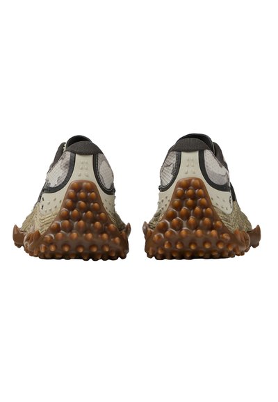 Paire de chaussures de sport avec semelles texturées beige et marron, ornées de picots en caoutchouc arrondis, vues de dos sur fond blanc.