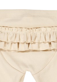 Leggings beige a coste con vita arricciata. Il tessuto è soffice, con una finitura texture e una leggera elasticità per il massimo comfort.
