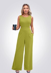 Groene mouwloze jumpsuit met wijde broekspijpen en zijzakken, met een aansluitende taille en een gladde textuur. Zwarte koffiebeker vastgehouden in de hand.