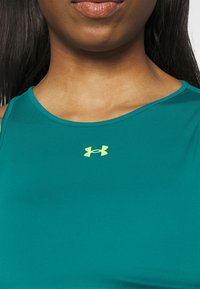 Morski sportowy top na ramiączkach z okrągłym dekoltem, z małym jasnooliwkowym logo na środku oraz gładką, elastyczną tkaniną.