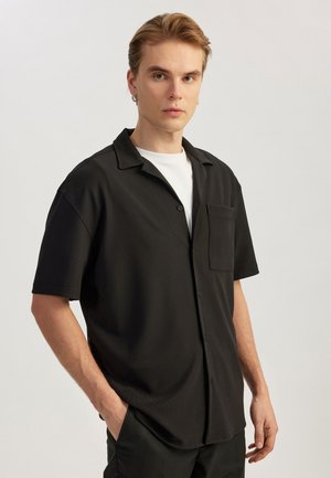Black short-sleeve button-up shirt with a pocket, made of textured fabric. Features a collar and a relaxed fit for comfort.