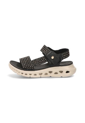 Sandalia negra de punta abierta con tiras brillantes, cierres ajustables de velcro y una suela gruesa beige con detalles de recortes circulares.