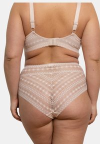 Ensemble de lingerie comprenant un soutien-gorge en dentelle beige clair et un slip taille haute, présentant des motifs géométriques, un tissu texturé et des bretelles réglables.