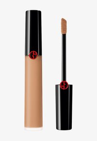 Flytende foundation i en sylinderformet, ugjennomsiktig beige beholder med en blank svart hette; inkluderer en applikator med doe-foot.