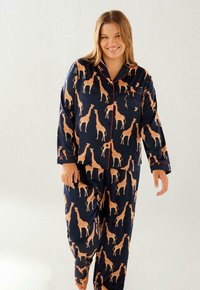 Navy pajama set featuring a giraffe pattern in tan, with contrasting red piping. The fabric appears soft and has a smooth finish.