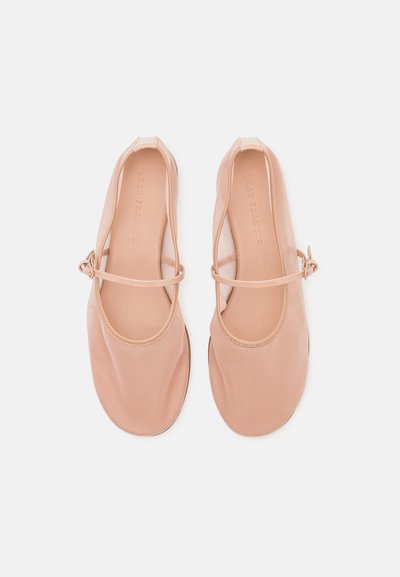Nude ballet flats made of soft fabric with a rounded toe, thin ankle strap, and minimalistic design. Smooth texture, no visible patterns.