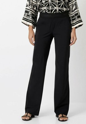 Black wide-leg trousers made from smooth fabric, featuring a textured elastic waistband with "LUXURY" band and a relaxed silhouette.