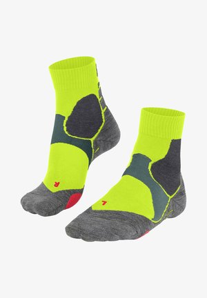 Grüne und graue Sportsocken mit einem geribbelten Bündchen, die mit kräftigen Farbmuster, strukturiertem Gewebe und roten Akzenten an Zehen und Ferse versehen sind.