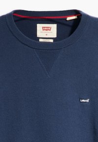 Mörkblå sweatshirt med ribbad rund halsringning och struktur, som har en liten vit Levi's-logga på bröstet och en röd detalj innuti kragen.