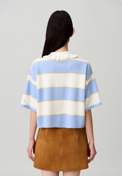 Maglione a righe blu e bianche con accenti gialli, maniche corte e colletto arricciato, abbinato a una minigonna in camoscio marrone.