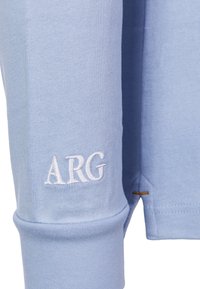 Light blue long-sleeve shirt with ribbed cuffs, featuring embroidered "ARG" logo on the sleeve and a contrasting stitch detail at the hem.