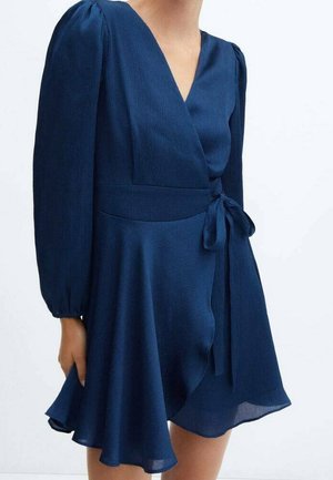 Navy blue wrap dress with long puffed sleeves, V-neckline, fitted waist, and asymmetrical flowing skirt tied at the side.