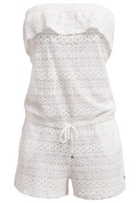 Combinaison courte blanche bustier en dentelle, avec motifs chevrons et floraux, et un cordon à la taille.