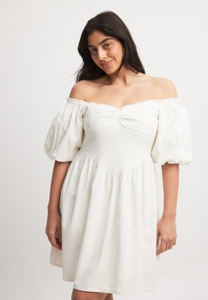 Robe blanche à épaules dénudées avec des manches bouffantes, dotée d'un corsage froncé et d'une jupe évasée. Fabriquée en tissu léger avec une texture douce.