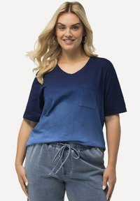 Marinblå gradient V-ringad t-shirt med korta ärmar och bröstficka, ihop med ljusblå byxor med snörning i ett mjukt, texturerat tyg.