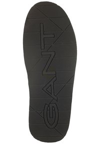 Suela de zapato de goma negra con patrones texturizados, prominente logotipo "GANT" y diseños geométricos para una mejor tracción y estabilidad.