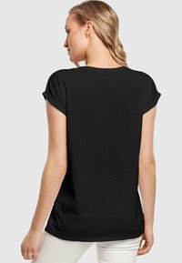 Sort kortærmet t-shirt med opsmøgte ærmer, let vævning, afslappet pasform og buet kant, båret med lyse bukser.
