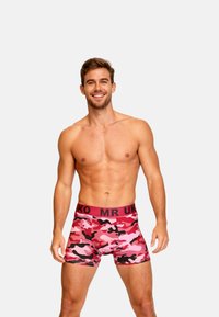 Rosa camouflage boxershorts med en svart midja som har texten "MR UK." Tyget verkar slätt med en åtsittande design.