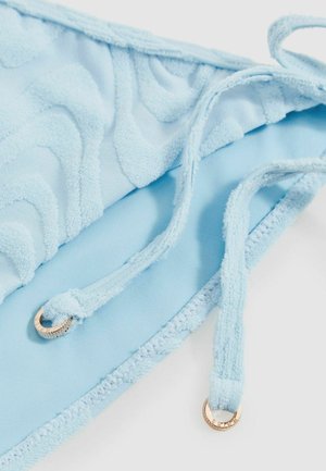 Šviesiai mėlynos bikini viršus su tekstūriniu bangų raštu, reguliuojamomis petnešėlėmis ir aukso spalvos aksesuarais. Minkšta, puri medžiaga.