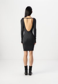 Must švarm, sobiv mini kleit pikade varrukatega, sügava seljareie avausega ja tekstuuriga sädelusega. Kandmine koos turske mustade pahkluutsükellidega.