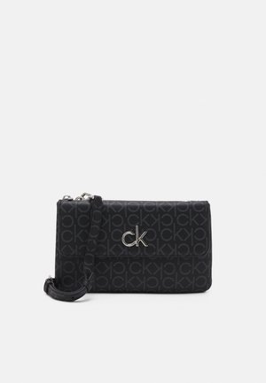 Černá crossbody taška s opakujícím se vzorem "CK", stříbrnými detaily, zipovým uzávěrem a nastavitelným popruhem pro všestranné nošení.