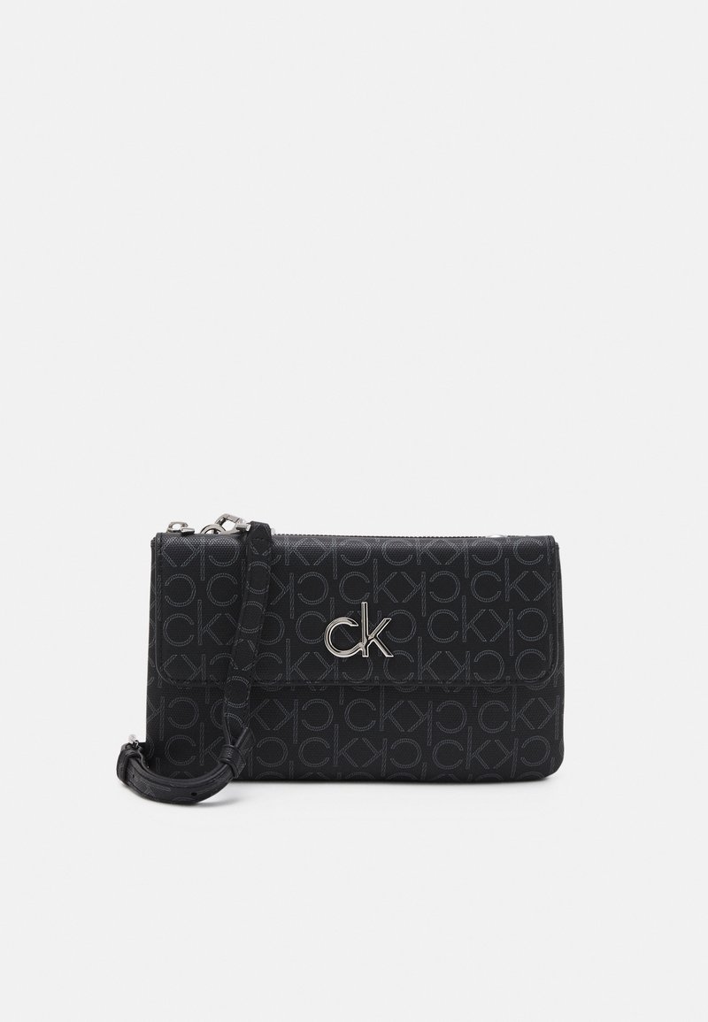 Černá crossbody taška s opakujícím se vzorem "CK", stříbrnými detaily, zipovým uzávěrem a nastavitelným popruhem pro všestranné nošení.