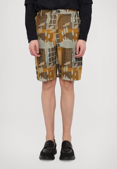 Brune og beige mønstrede shorts med et gitterdesign, der har frynset kanter, en knaplukning og sidelommer, parret med sorte sko.