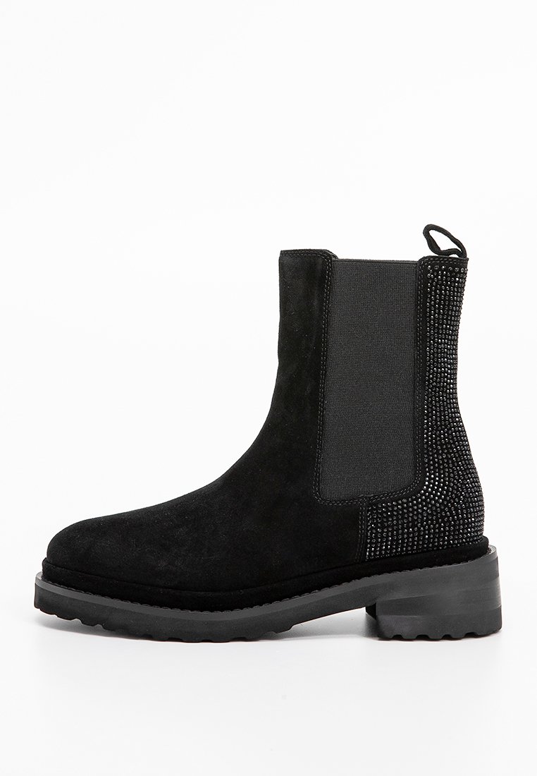 Botte de cheville en suède noir avec panneaux latéraux élastiques et accents cloutés. Semelle épaisse noire avec motif pour adhérence. Design à bout rond.