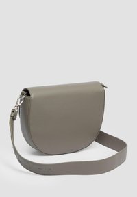 Graue Leder-Crossbody-Tasche mit einer runden Form, glatter Textur und verstellbarem Trageriemen mit eingeprägtem Branding. Metallbeschläge sind vorhanden.