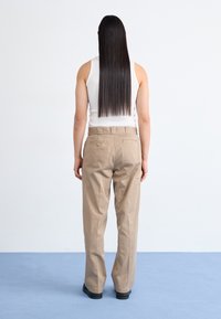 Pantaloni khaki, larghi e realizzati in cotone, con vita alta, due tasche posteriori e una silhouette a gamba dritta.