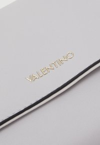 Gray leather clutch featuring a gold "Valentino" logo, with a black accent trim along the edge and a smooth texture.