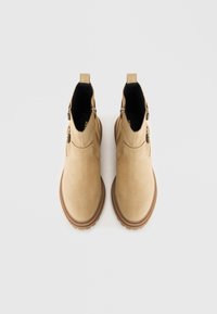 Bottines beiges en daim, dotées d'un bout arrondi, d'une semelle en caoutchouc contrastante et de fermetures éclair latérales pour un enfilage facile.