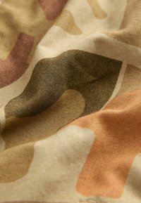 Tessuto a camuflaggio in cotone caratterizzato da forme irregolari in tonalità terrose di verde, beige e ruggine, con una texture sottile e motivi variati.