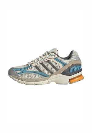 Chaussure de course en mesh beige et bleu avec semelle rembourrée, fermeture à lacets et détail de soutien du talon orange, conçue pour un usage sportif.