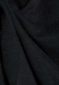 Gros plan d’un tissu tricoté noir et doux avec des plis subtils et un tissage texturé.