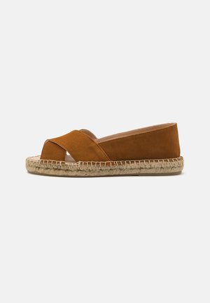 Brun ruskinds-espadrille med krydsremdesign, jutesnøre-sål og flad hæl. Har en blød tekstur og åben tå.