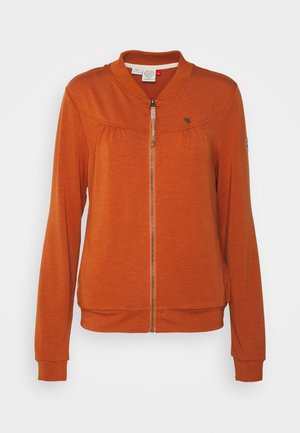 Chaqueta de color naranja quemado con cremallera, mangas largas, cuello redondo, puños y dobladillo acanalados, y pequeños detalles metálicos con logo en el pecho y la manga.