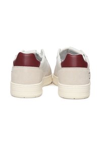 Sneaker bianchi con tallone in pelle rossa e dettagli in suede beige. Forma arrotondata, materiali testurizzati e suola in gomma con scanalature orizzontali.