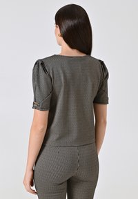 Top a fantasia bianco e nero con maniche corte a sbuffo, tessuto texture e design attillato, che presenta un sottile motivo a labrador.