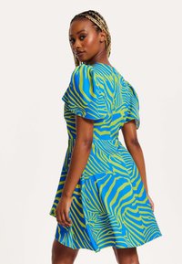 Blue and green short dress with puff sleeves, featuring a striped pattern. The fabric appears smooth and lightweight, creating an A-line silhouette.