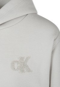 Felpa bianca in tessuto strutturato con logo cK ricamato in una tonalità più chiara. Il design include un cappuccio con stringhe e dettagli a coste.