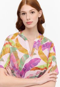 Kurzarmbluse mit einem lebhaften tropischen Blattmuster in Pink, Grün, Orange und Lila. Besitzt einen Schlüssellochausschnitt und ein leichtes Material.