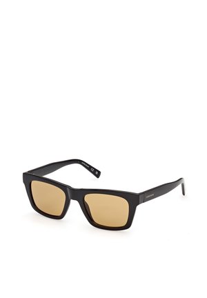 Schwarze rechteckige Sonnenbrille mit braunen Gläsern und dünnen Bügeln, schräg auf weißem Hintergrund platziert.