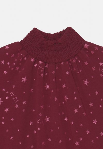 Top bordô com colarinho alto com franzido, apresentando padrões de estrelas em glitter rosa e os números "Nº21" e "Nº2" impressos de forma esporádica.