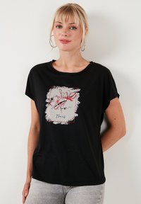 Zwarte T-shirt met korte mouwen heeft een bloemendessin in rood en wit binnen een rechthoekig ontwerp, gemaakt van zacht, ademend materiaal.