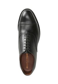 Scarpa da uomo in pelle nera caratterizzata da una punta arrotondata, dettagli cuciti e allacciatura frontale. L'interno presenta una soletta marrone con scritte dorate.