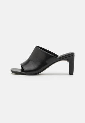 Mule noire à bout ouvert avec un talon bloc de hauteur moyenne et une tige en cuir lisse, présentée en profil latéral sur un fond blanc.