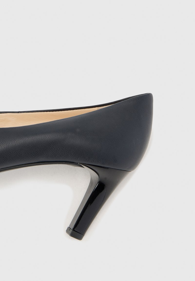 Czarna skórzana szpilka z ostrym noskiem, z lakierowaną obcasem i gładką teksturą. Wnętrze jest beżowe.