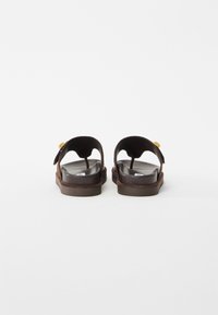 Brown open-back sandals with adjustable straps and gold buckle details, shown from the rear on a white background.